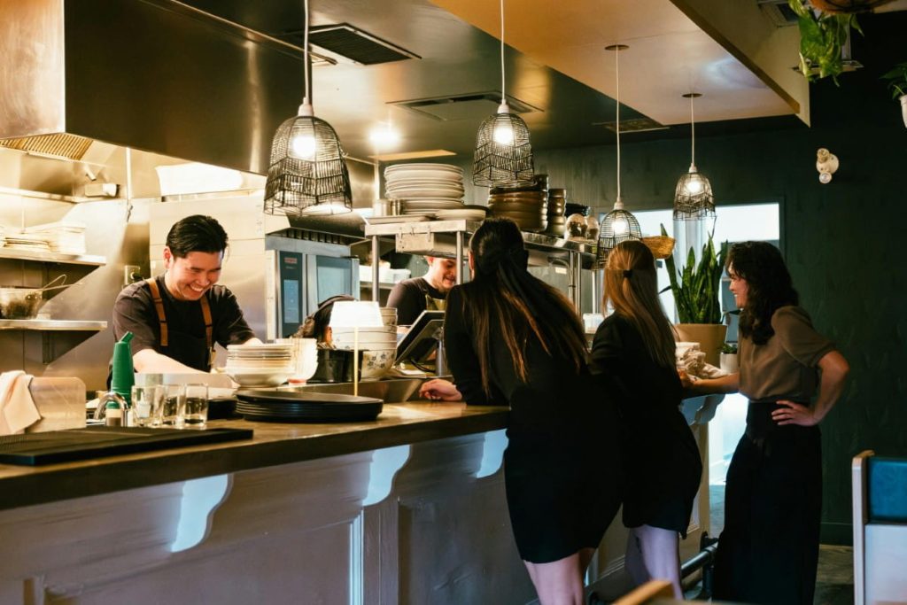 Busy restaurant interior with staff and customers at the counter, representing commercial property and business real estate.