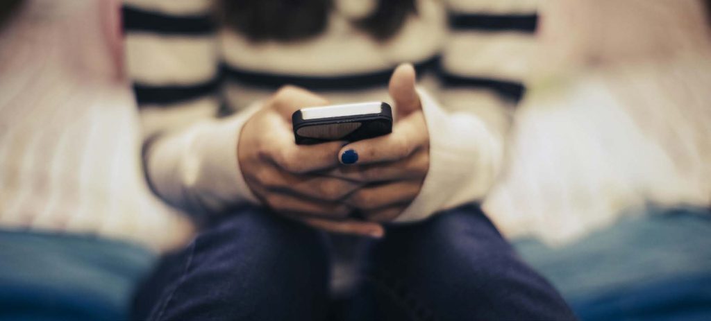 Close-up of a person holding a smartphone, representing mobile communication, alerts, or real estate messaging.
