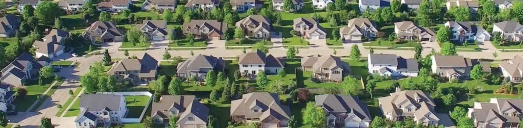 Aerial view of a suburban neighborhood with single-family homes, tree-lined streets, and neatly maintained lawns.